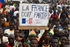 Protesters hold an anti-France placard during a demonstration on independence day in Niamey