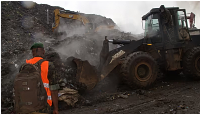 Rescue workers search through a heap of refuse after it collapsed at Conakry’s largest landfill