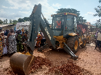 The Regional Minister operating an equipment to signify the commencement of construction works.