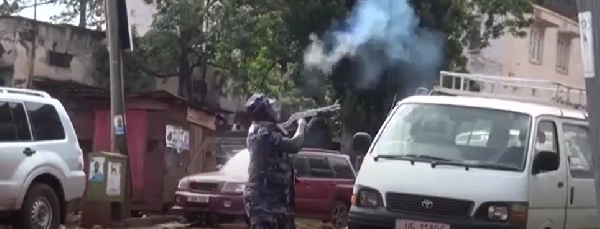Ugandan police holding gun and shooting at protesters.   -   Copyright 
