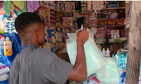 A young is seen in a shop holding what is suspected to be diapers