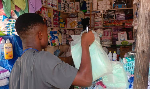 A young is seen in a shop holding what is suspected to be diapers