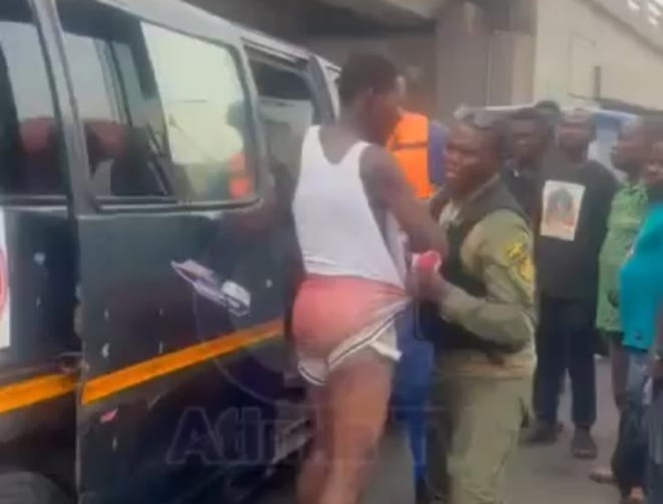 The trotro driver being arrested by an officer for overpricing transport fares
