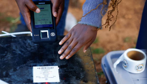 A polling agent scans a box containing electoral materials with a BVVM