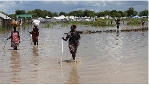 Women wade through flood waters after the River Nile broke the dykes in Pibor