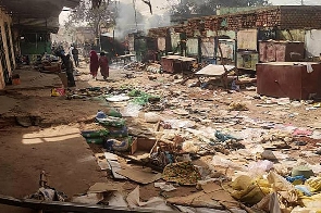 People walk among scattered objects in the market of el-Geneina, the capital of West Darfur