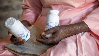 Florence Makumene holds HIV medication that she received through funding