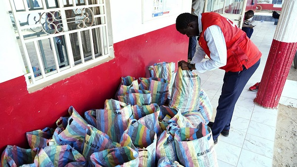 A member of the Gambia Red Cross looks through sacks of collected cough syrups in Banjul