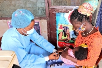A health practitioner immunising a child