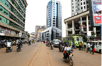 Motorcycle taxi drivers, known locally as boda-bodas, ride with passengers on a street of Kampala
