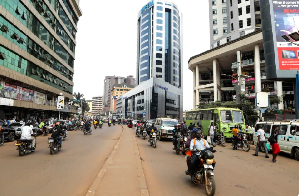 Motorcycle taxi drivers, known locally as boda-bodas, ride with passengers on a street of Kampala