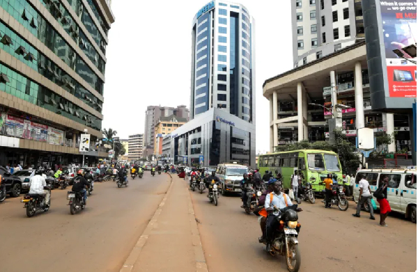 Motorcycle taxi drivers, known locally as boda-bodas, ride with passengers on a street of Kampala