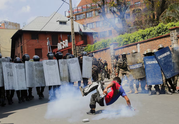 A protester falls down, near a tear-gas canister deployed by riot police