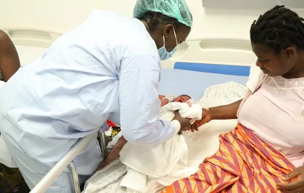 A newly delivered born baby being handed over to the mother by a midwife