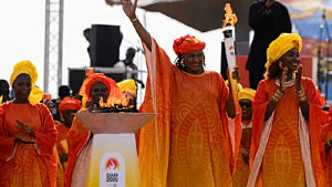 Senegalese basketball legend Mame Maty Mbengue lights a torch from the cauldron during a ceremony