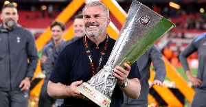 Ange Postecoglou holding the Europa League trophy while beaming with smiles