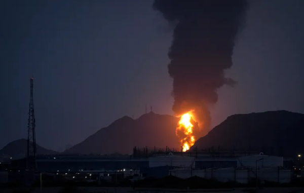 Fire and plume of smoke is visible after debris of an intercepted Iranian drone hit an oil facility