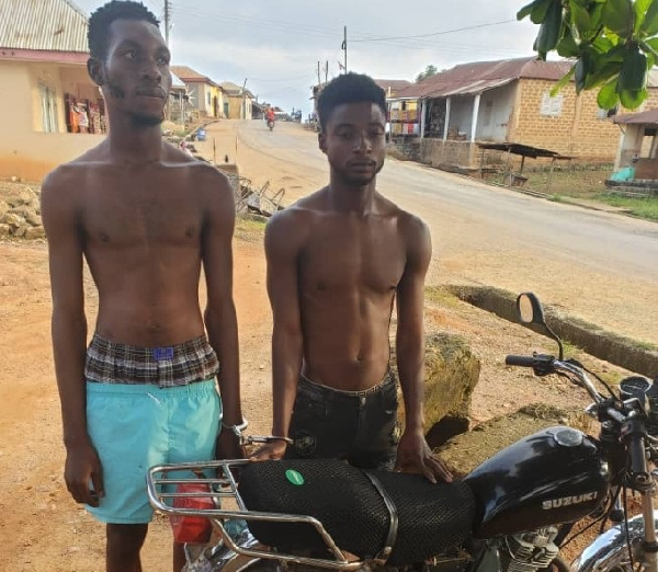 The convicts standing beside the stolen motorbike