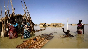 South Sudanese refugees try to repair their hut in flooded waters from the White Nile