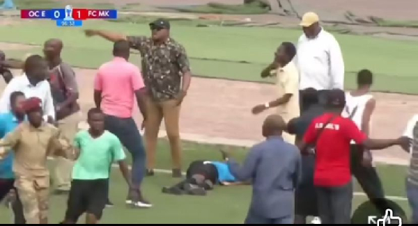 The referee on the floor surrounded by angry fans