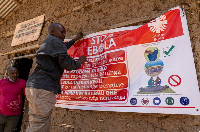 A man hangs an Ebola awareness banner in the Kigonze camp in Bunia