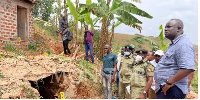 Police officers gather at the cave-like hole where four suitcases full of human skulls were discover