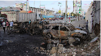 People gather near the wreckages of vehicles destroyed at the scene of the explosion