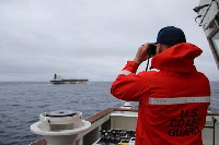 A U.S. Coast Guard official looks through binoculars at the ship Marinera (Ex-Bella 1)