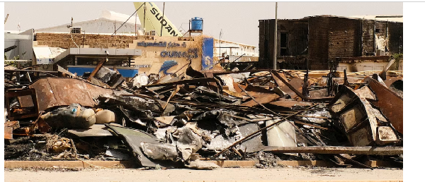 A view of a burned building and the tail of a Sudan Airways aircraft amid debris at Khartoum Airport