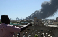 A man watches as smoke billows after a drone attack on Port Sudan