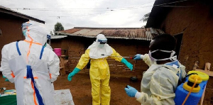 A healthcare worker, who volunteered in the Ebola response, decontaminates his colleague