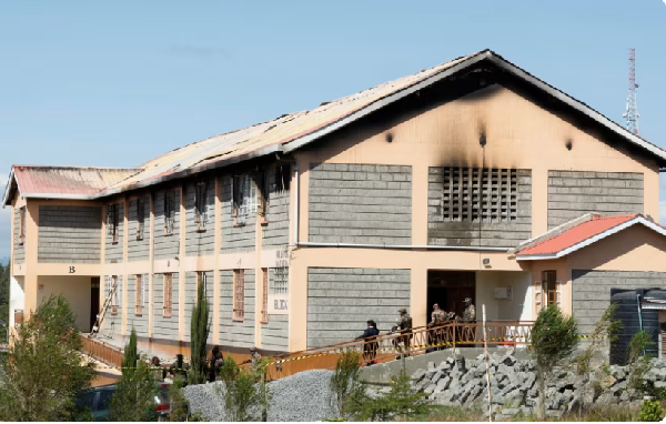 Security officers stand outside a burnt dormitory at the Utumishi Girls' Academy Senior School