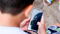 A boy holding a smartphone in his hands on which the logo of the short video app TikTok