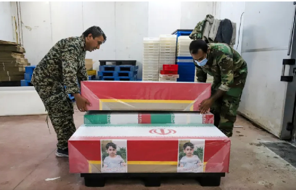 Mourners prepare the coffins of children who were killed in a strike on a primary school in Iran