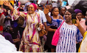 Irene Naa Torshie Addo in pink scarf, waves at traders