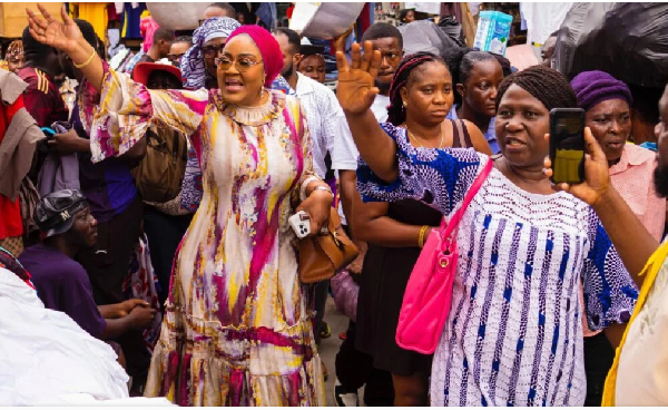 Irene Naa Torshie Addo in pink scarf, waves at traders