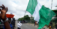 A man carries a Nigerian flag protesting against the economic hardship on the street in Lagos