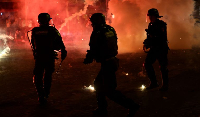 Police officers protect themselves from flares after Paris Saint-Germain won  UEFA Champions League
