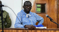 Kizza Besigye stands in the dock at the courtroom where he was charged with inciting violence