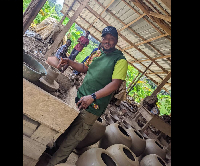 Etsey Atisu poses with a pot he made at Vume, the Home of Pottery
