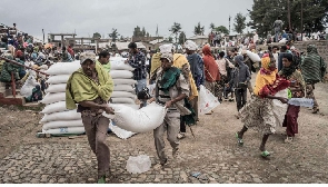 Men carry a sack of wheat during food aid distribution by WFP for IDPs in Debark, Ethiopia