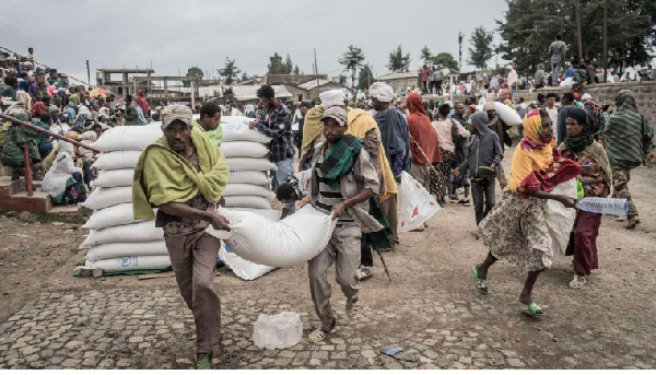 Men carry a sack of wheat during food aid distribution by WFP for IDPs in Debark, Ethiopia