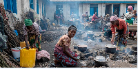 Anociata Nyiranzarura prepares food for her displaced family at a schoolyard shelter