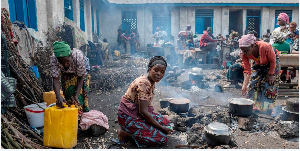 Anociata Nyiranzarura prepares food for her displaced family at a schoolyard shelter