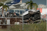 Investigators walk near damaged vehicles Sunday at Miami International Airport