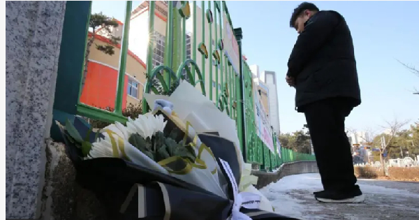 Locals lay flowers for di school gate to mourn di eight-year-old student