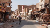 A member of the Sudanese Armed forces walks between damaged buildings