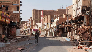 A member of the Sudanese Armed forces walks between damaged buildings