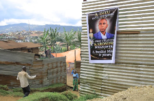 People walk past a banner featuring slain local official Marie-Celestin Karondwa