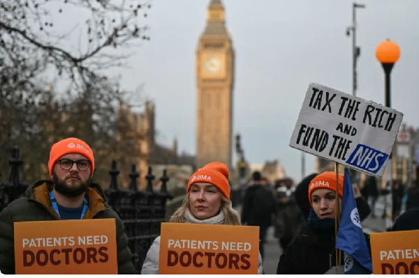 Staff members hold placards as they stand on a picket line during the first day of a five-day strike